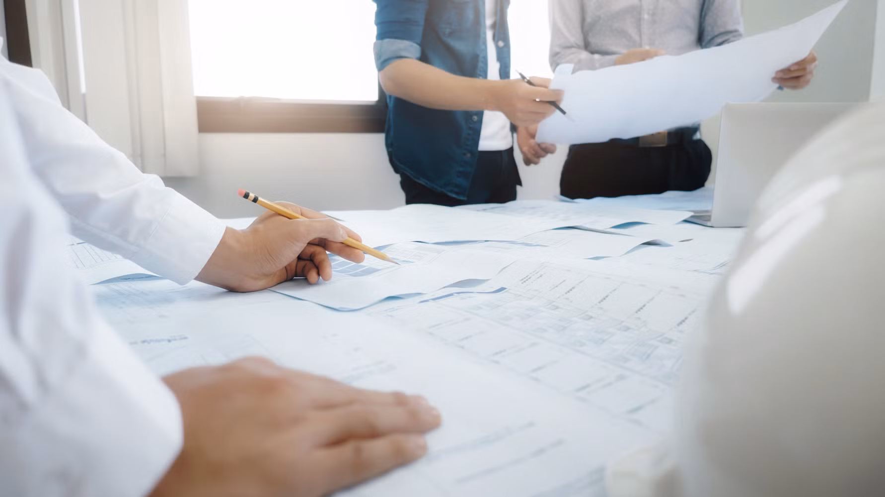 Ritningar på ett bord där det står personer runt om.