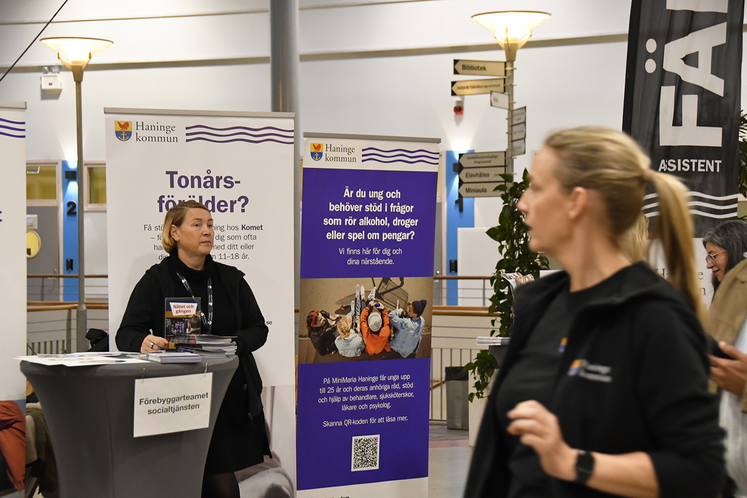 En person står i en informationsmonter från Haninge kommun med budskap riktade till tonårsföräldrar och unga som behöver stöd kring alkohol, droger eller spel. 