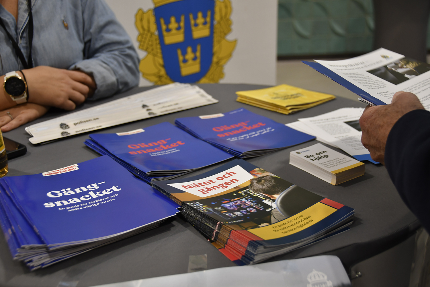 Uställningsbord hos Polisen med broschyrer och material om gängproblematik och nätbaserad påverkan, inklusive titlar som 'Gängsnacket' och 'Nätet och gängen'.