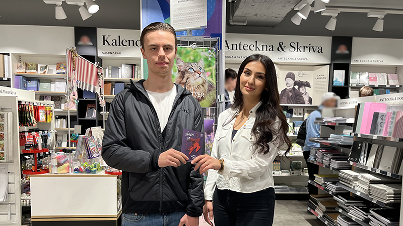 En ung kille och en kvinlig lärare håller i en bok.