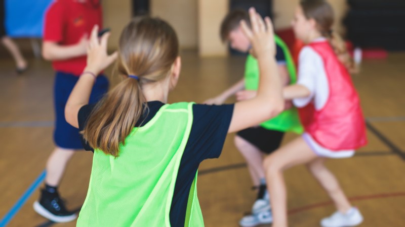 Basketmatch med flickor och pojkar på mellanstadiet.