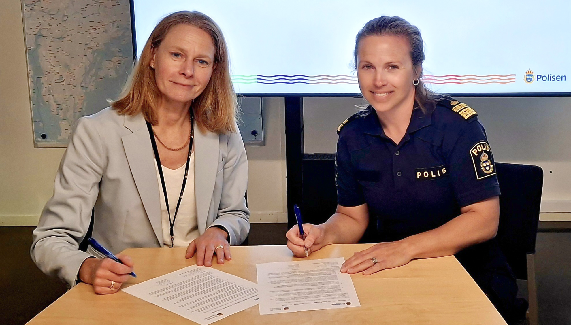 Två kvinnor signerar dokument. 