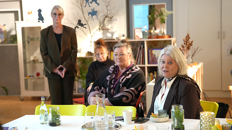 En kvinna sitter vid ett bord och pratar.