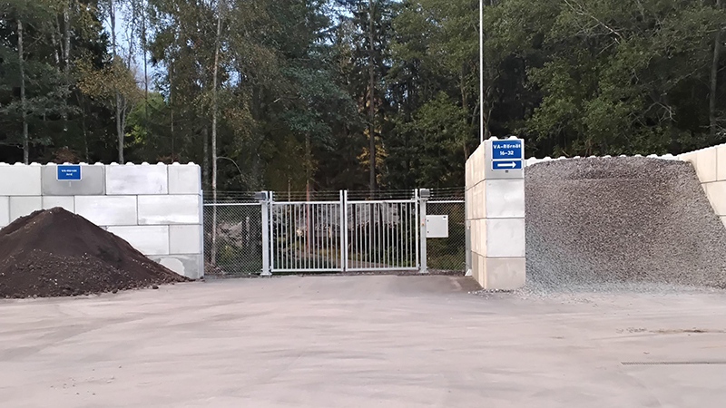 Betongväggar och en stängd grind omgiven av skog