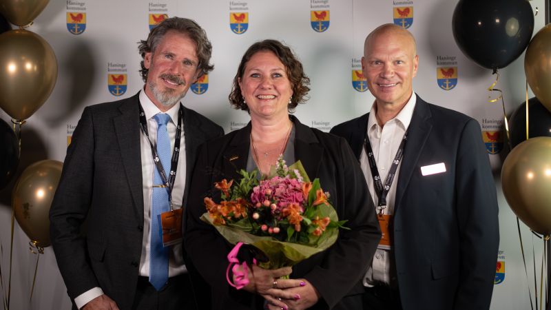 Pia med blombukett flankerad av Sven och Daniel. Ballonger, Haningeemblem i bakgrunden. 