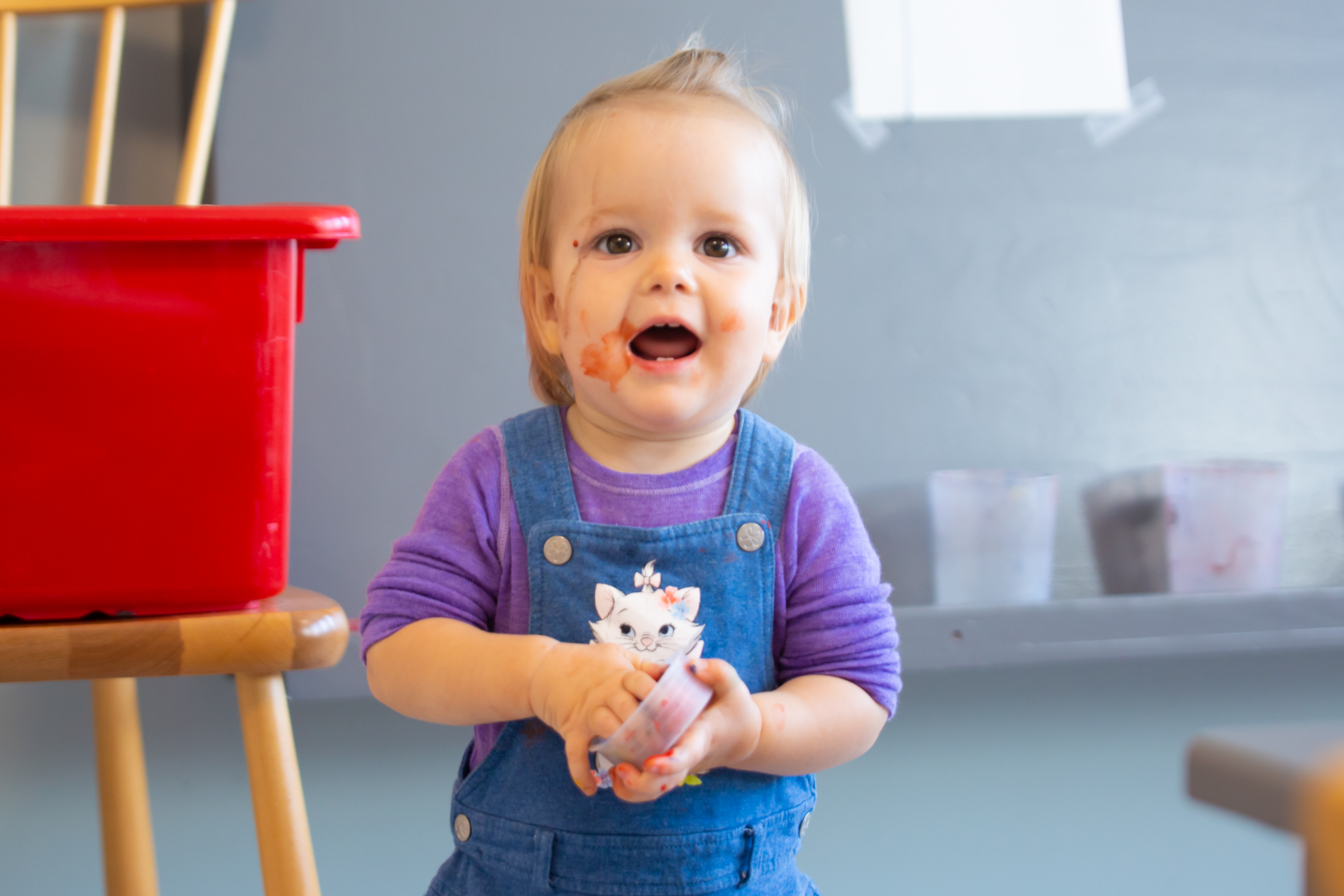 Litet barn med färg i ansiktet skrattar åt fotografen