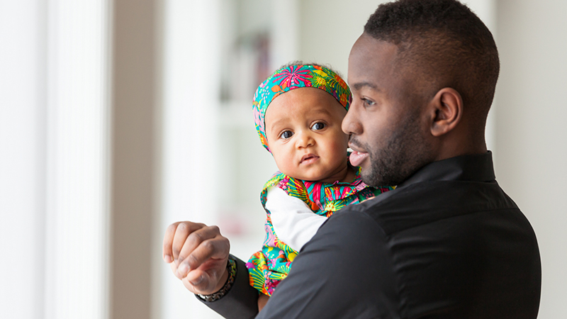En pappa håller en liten bebis i famnen